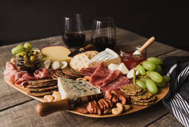 Close up of charcuterie board and glasses of wine on wooden table. Close up of charcuterie board and glasses of wine on wooden table. in Kingston, ON, Canada prosciutto brie stock pictures, royalty-free photos & images