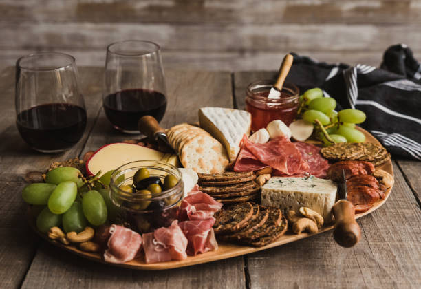 Close up of charcuterie board and glasses of wine on wooden table. Close up of charcuterie board and glasses of wine on wooden table. in Kingston, ON, Canada prosciutto brie stock pictures, royalty-free photos & images