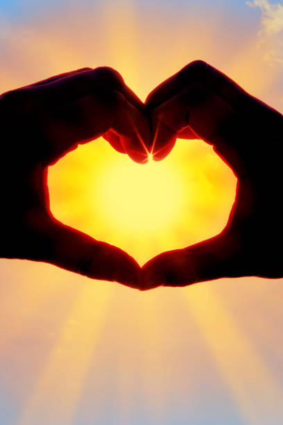 istock Hands forming a heart shape over the sun 1207580018