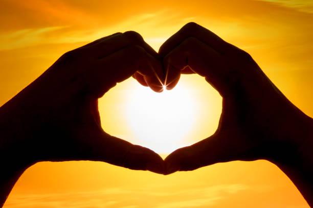 istock Hands forming a heart shape over the sun 1207580058