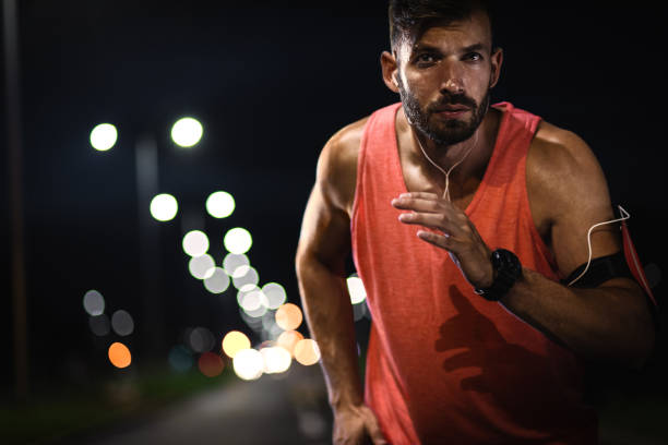 istock Man running through the city at night. 1207580355