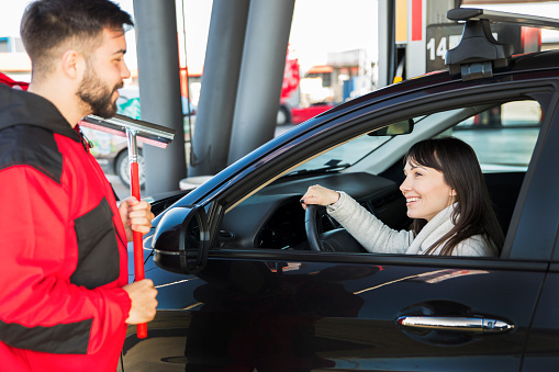 Man at petrol station cleaning car window