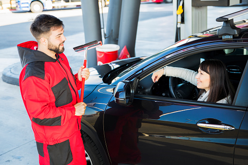 Man at petrol station cleaning car window