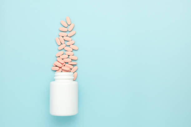 istock Vitamin tablets sprinkled from the bottle on a blue background. Advertisement concept of medicine for children 1207582126