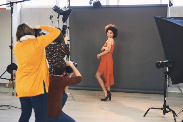 istock Three attendees  standing in studio and taking photos of beautiful mixed race female model. 1207585673