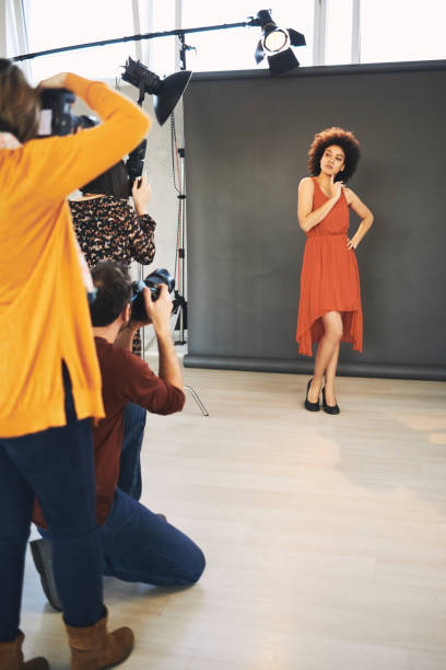 istock Three attendees  standing in studio and taking photos of beautiful mixed race female model. 1207585802