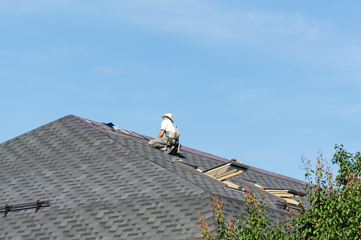 The man on the roof. Photo of a worker repairing the roof of the house.
