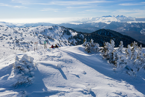 Drone panorama with two skiers resting on top of Ciucas Mountains in winter season.