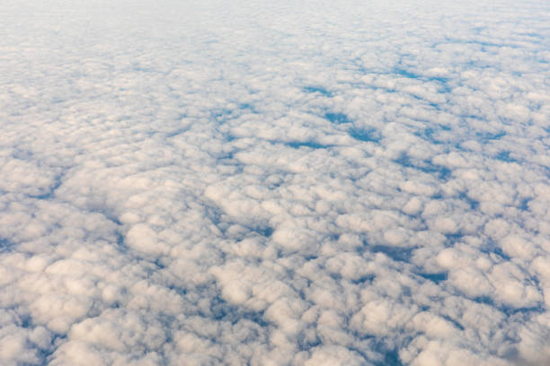 Aerial view of fluffy clouds through an airplane window
