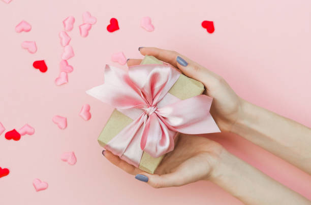 istock Hands Holding a Valentine's Day Present on Pink Background. 1207601995