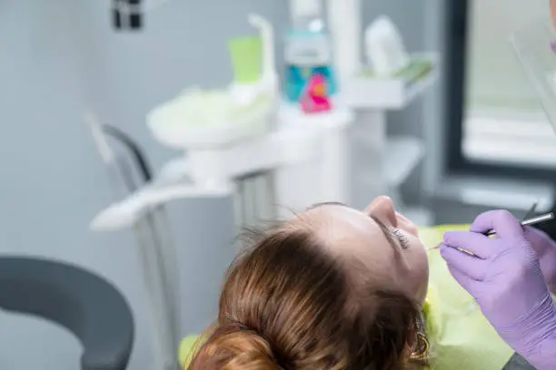 Dentist examing female patient in dental clinic. Modern medical equipment.