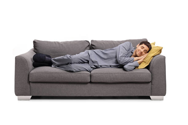 istock Man in pajamas sleeping on a sofa and dreaming a beautiful dream 1207612291