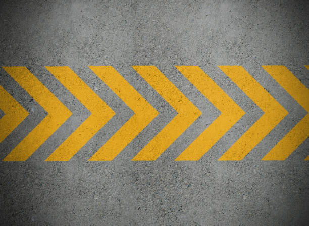 istock Yellow arrows line painted on concrete wall 1207612338