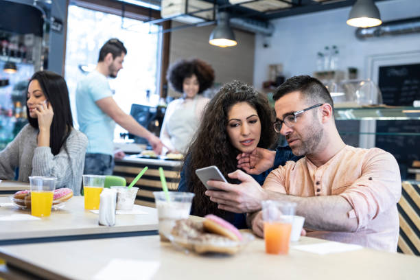 istock Couple sitting in bar and using smart phone 1207615177