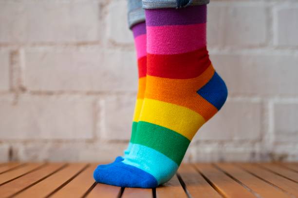 istock Feet standing on tiptoe with colored socks. 1207619360