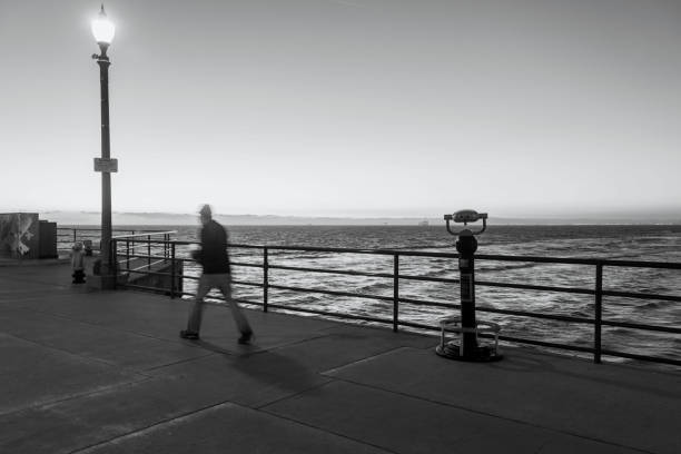 istock Man Walking Briskly on the Huntington Beach Pier at Twilight 1207632877
