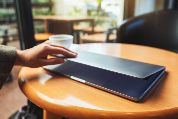 istock a woman close and open a laptop computer on table after finished using it 1207642947