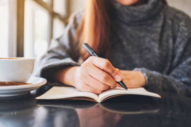 istock a woman writing on a blank notebook on the table 1207642948