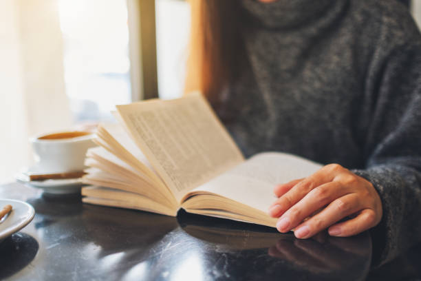 istock a beautiful woman holding and reading a book with coffee cup on the table 1207643993