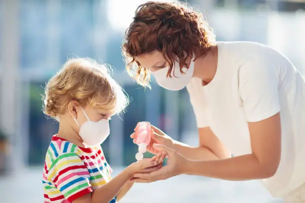 Photo of Mother and child with face mask and hand sanitizer