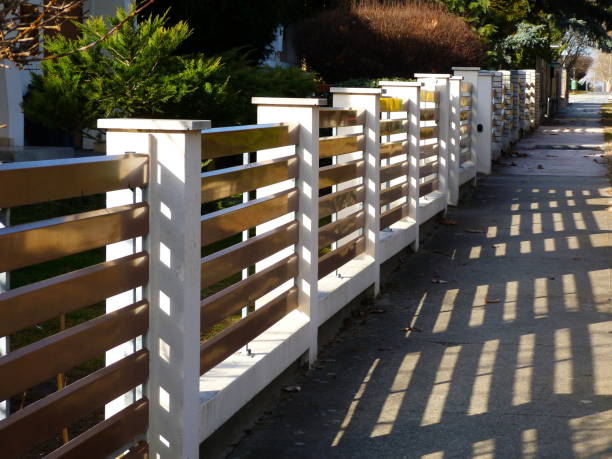 stucco finished fence piers with horizontal brown metal slats stock photo