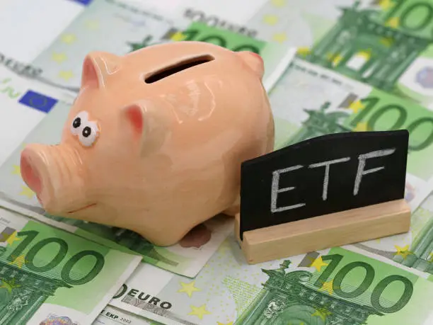 Photo of piggy bank and blackboard which shows ETF on hundred euro banknotes, concept of exchange-traded fund investment