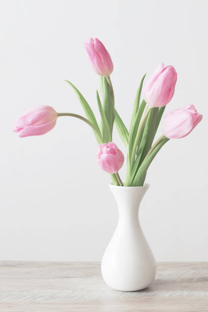 istock pink tulips in white ceramic vase on wooden table on background white wall 1207665414