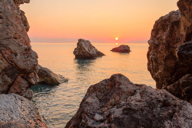 alba sulla costa rocciosa del mare grandi rocce e una roccia vicino all'acqua - beauty in nature cloud rocky coastline rock foto e immagini stock