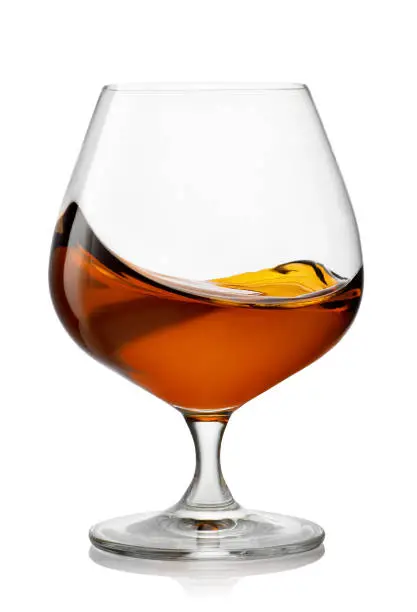 splash of brandy in snifter glass isolated on white background