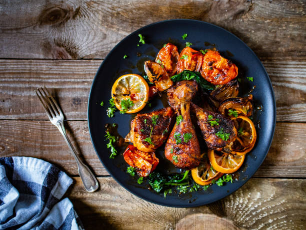 나무 테이블에 검은 접시에 제공되는 구운 치킨 드럼스틱과 야채 - grilled barbecue chicken meat 뉴스 사진 이미지