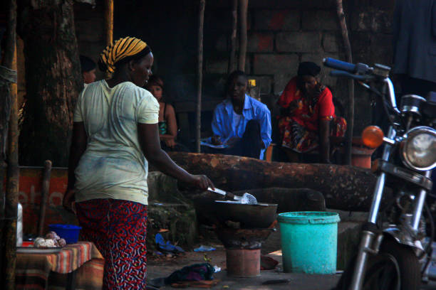 kobieta gotuje na typowym straganie z jedzeniem ulicznym przy głównej drodze w konakry, gwinei, afryce zachodniej - africa african descent cooking african culture zdjęcia i obrazy z banku zdjęć