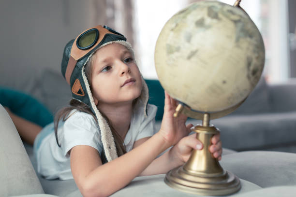 小さな女の子は地図を調べる - travel globe student journey ストックフォトと画像