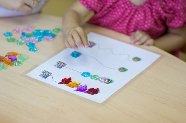 子供の手は、細かい運動能力を開発するためにカラフルな石で遊んで - fine motor skills ストックフォトと画像