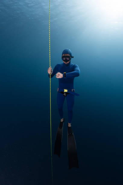 istock Freediver hangs on the rope in the depth and looks at his watch 1207683031