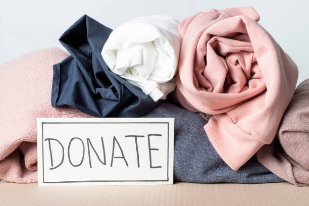 istock A stack of multi-colored clothes and the inscription Donate front view close-up. 1207683918