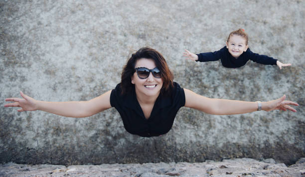 istock Mother and daughter with arms outstretched 1207684567