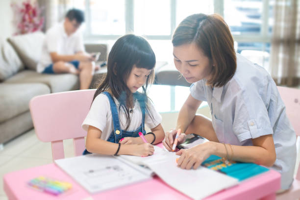 istock Mother guiding daughter with her homework 1207685837