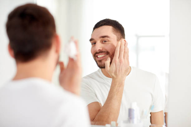 istock happy man applying shaving foam at bathroom mirror 1207687765