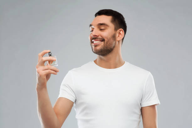 istock smiling man with male perfume over gray background 1207687965