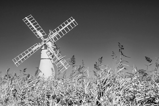 Black and white photo of the white windmill in the countryside on a bright and sunny day
