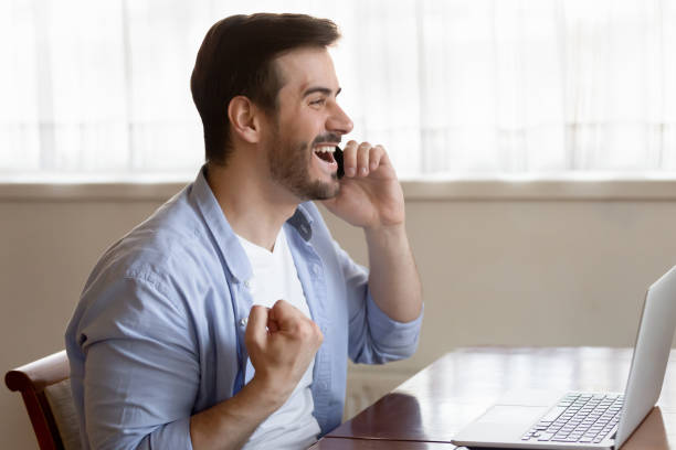 istock Excited millennial man triumph getting amazing news on cell 1207691955