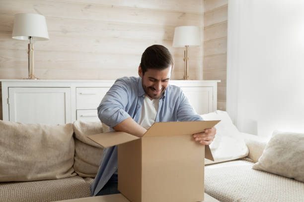 istock Excited male client unpack internet delivery package 1207691979
