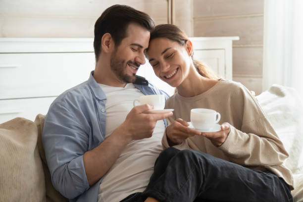istock Loving young couple hug on couch drinking tea 1207692012