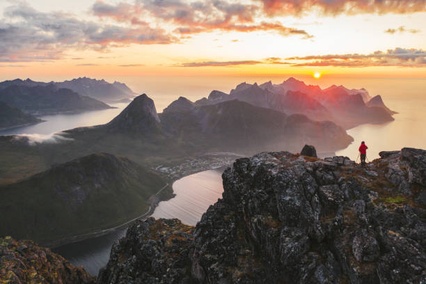 vista aérea del hombre de pie en el pico de la montaña en la isla de senja - sol de medianoche fotografías e imágenes de stock