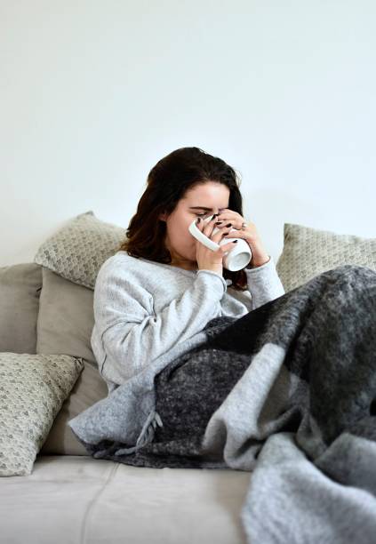 istock The young girl drinks tea on a gray sofa 1207694659