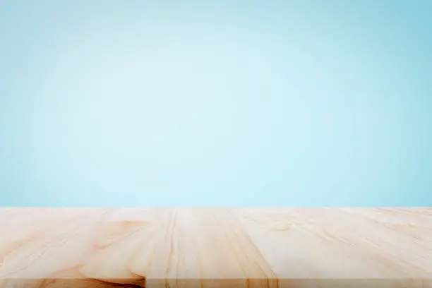 Empty wooden deck table over light blue wallpaper background for present product.