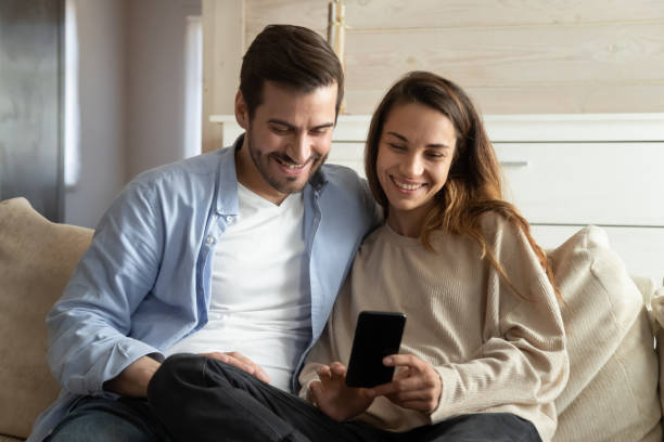 istock Happy young man and woman relax at home using cellphone 1207696838