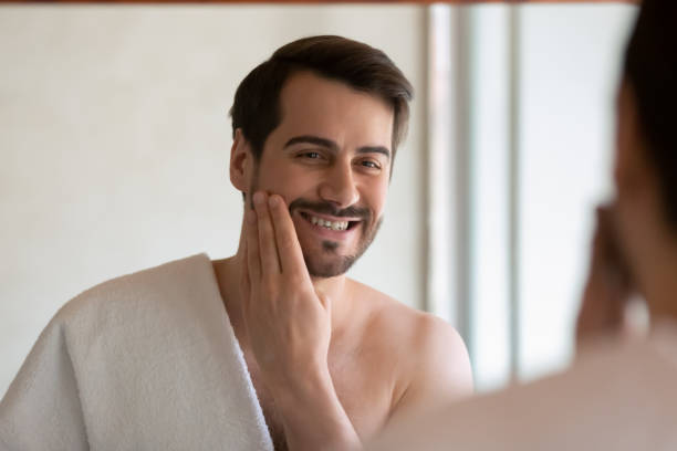 istock Smiling millennial man apply face lotion after shaving 1207696880