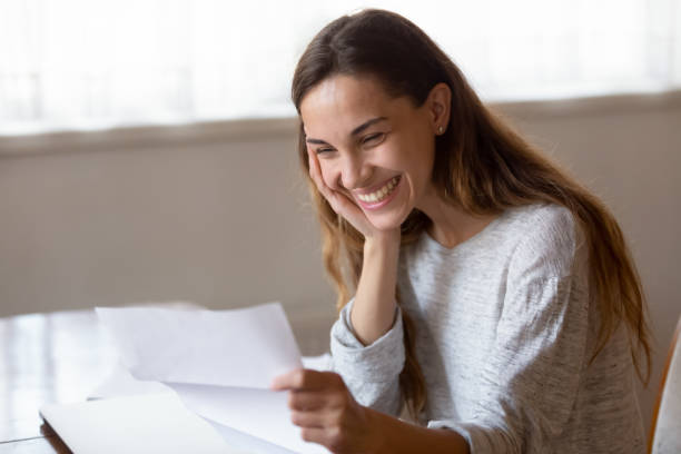 Happy young woman read good news in paper letter Smiling young woman sit at table at home reading good news in post correspondence, happy millennial girl feel overjoyed receive pleasant postal paper correspondence mail, approval or positive decision college acceptance letter stock pictures, royalty-free photos & images