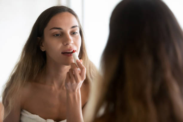 istock Young woman in towel doing makeup with red lipstick 1207696919
